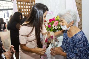 Clau Camargo entrega flor para idosa