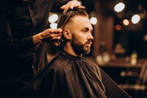jovem na barbearia aparando cabelo